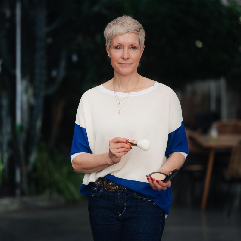 Caroline Montfort - Hair-und-Make-up-Stylistin - hält einen Makeup-Pinsel in der Hand.